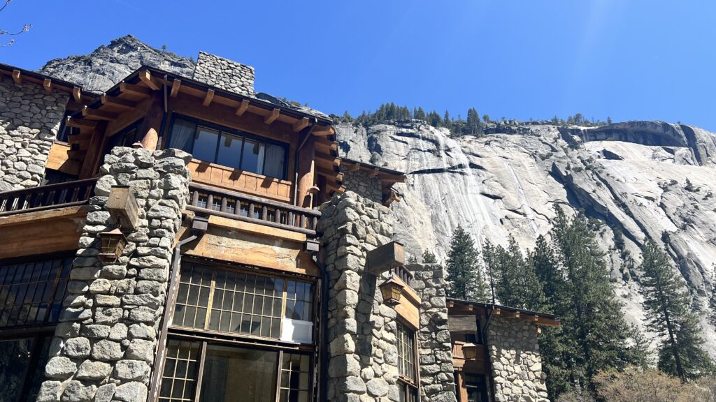 The stone and wood exterior of the historic and majestic Ahwahnee stands in front of the Royal Arches