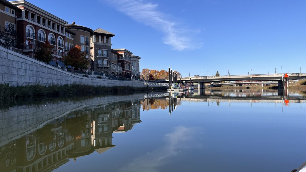 Picture of Napa River on a calm day. This image shows some of the downtown businesses and it is what you would see as you kayak the Napa River.