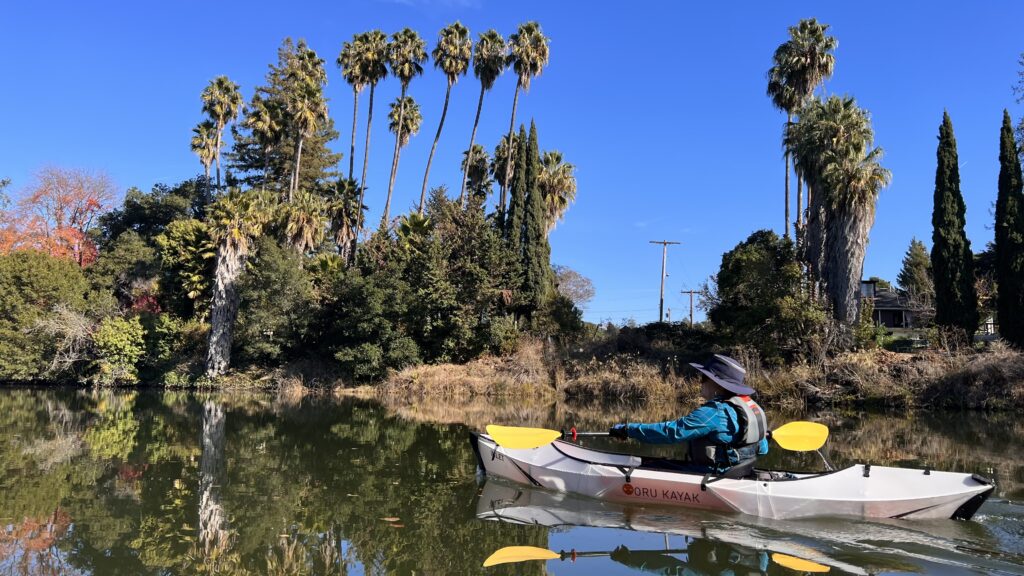 Picture of Napa River on a calm day showing a kayaker paddling the Napa River near Oxbow Commons.