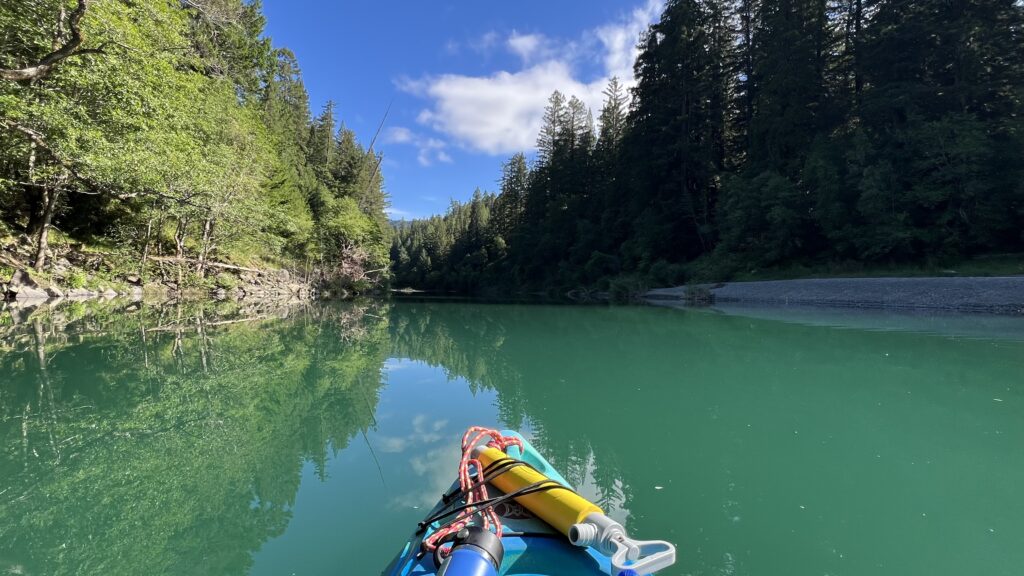 Photo of a kayak floating down the Eel River.  The river parallels the Avenue of The Giants and provides kayakers an incredible route through old growth redwoods.
